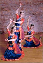 Three dancers in traditional Indian performance attire showing a traditional dance pose.
