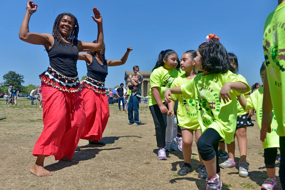 Global Education Center's Afro Latin adult dance troupe are dancing with some Latino children at Bicentennial Park during a community outreach.